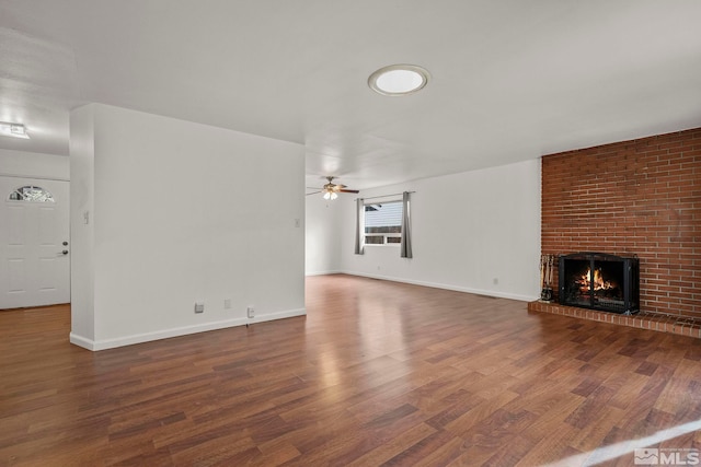 unfurnished living room with ceiling fan, dark hardwood / wood-style floors, and a brick fireplace