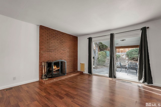 unfurnished living room with hardwood / wood-style floors and a brick fireplace