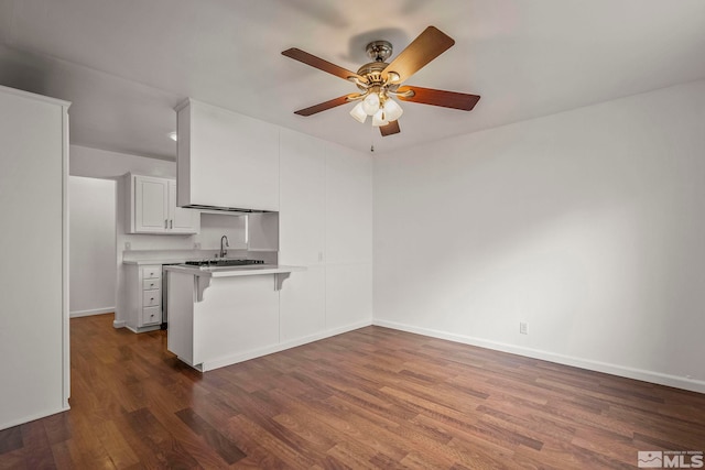 kitchen featuring kitchen peninsula, dark hardwood / wood-style flooring, sink, white cabinetry, and a breakfast bar area