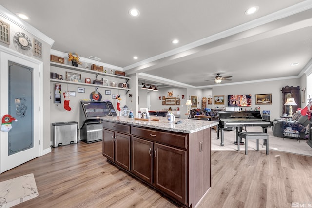 kitchen featuring ceiling fan, a center island, dark brown cabinets, and light hardwood / wood-style floors