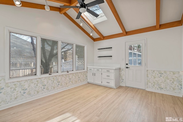 interior space featuring beam ceiling, a skylight, white cabinetry, and plenty of natural light