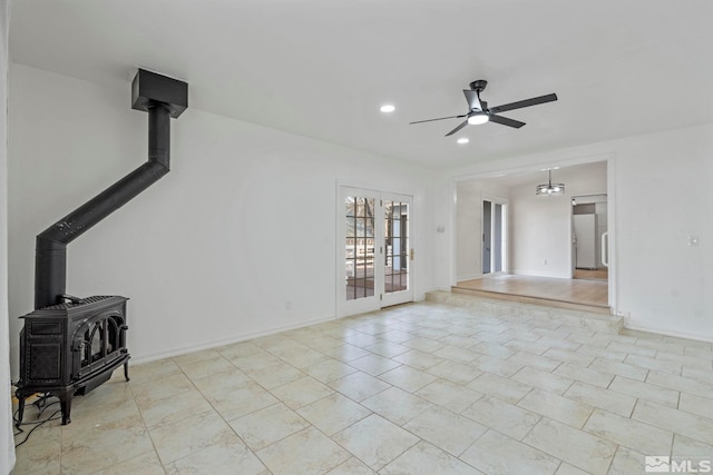 unfurnished living room with french doors, light tile patterned floors, a wood stove, and ceiling fan