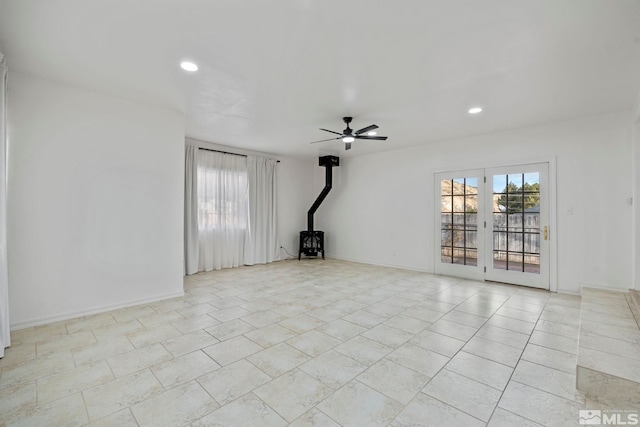 unfurnished living room with a wood stove, ceiling fan, and french doors