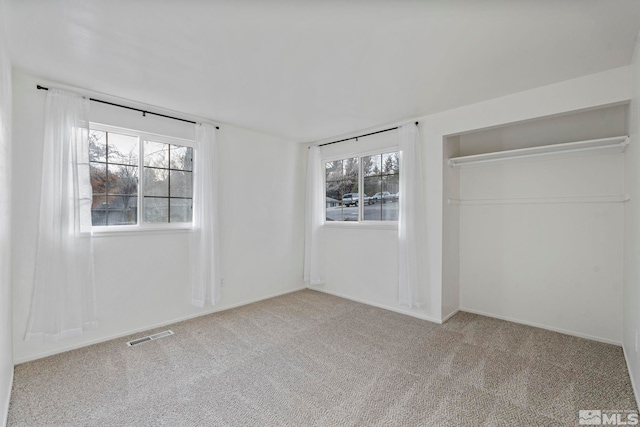 unfurnished bedroom featuring a closet, light colored carpet, and multiple windows