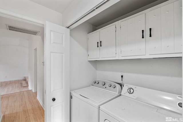 laundry room featuring washer and clothes dryer, cabinets, and light hardwood / wood-style flooring