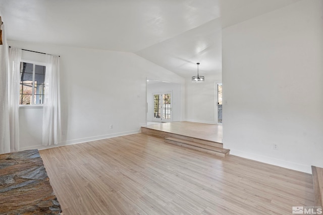 unfurnished living room with a healthy amount of sunlight, vaulted ceiling, and light hardwood / wood-style flooring