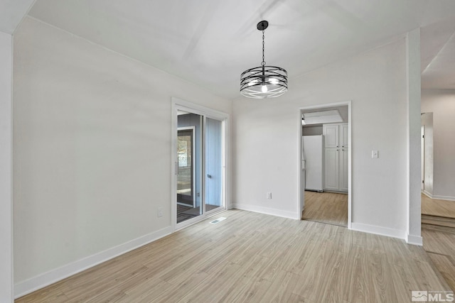 unfurnished dining area featuring light wood-type flooring and an inviting chandelier