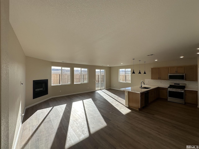 kitchen with sink, dark wood-type flooring, stainless steel appliances, kitchen peninsula, and decorative backsplash