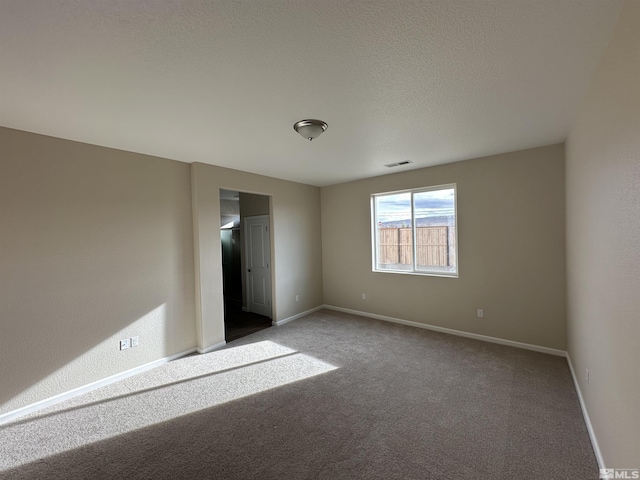 carpeted empty room with a textured ceiling