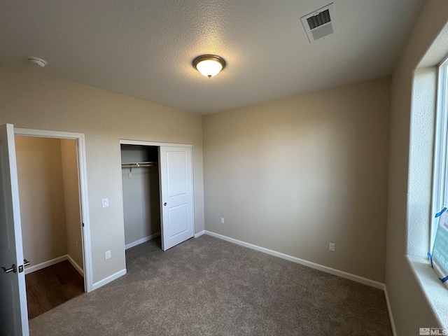 unfurnished bedroom with a closet, carpet, and a textured ceiling