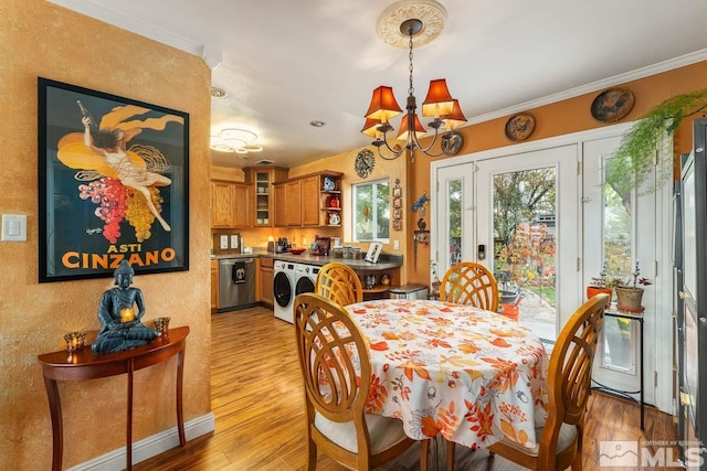 dining area featuring washer / dryer, light hardwood / wood-style floors, an inviting chandelier, and crown molding