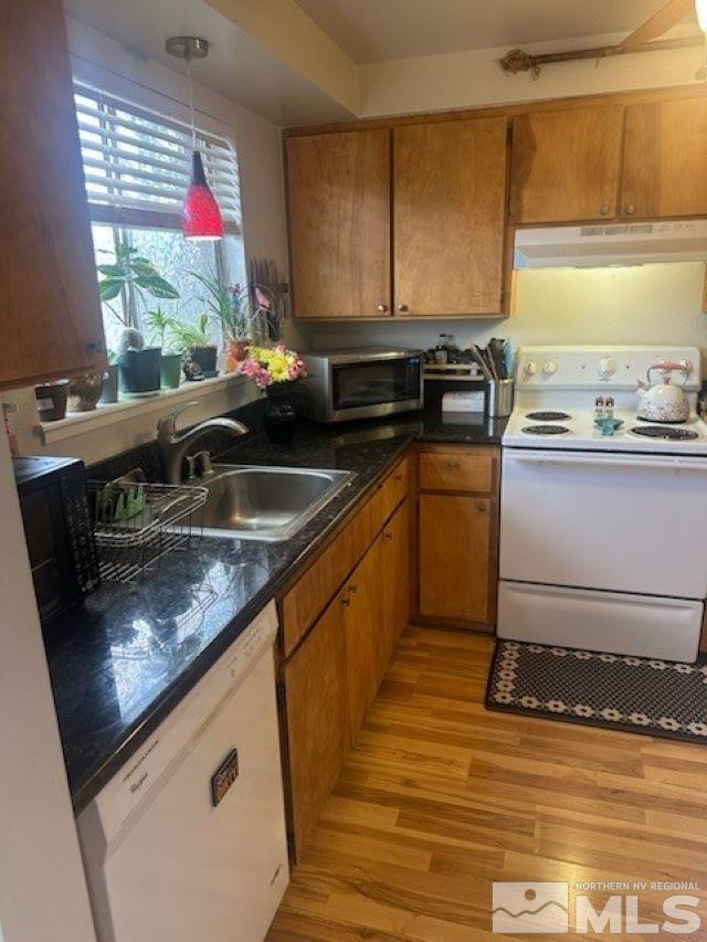 kitchen with pendant lighting, white appliances, light hardwood / wood-style floors, and sink