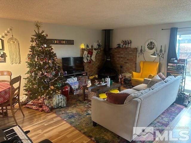 living room with hardwood / wood-style floors, a textured ceiling, and a wood stove