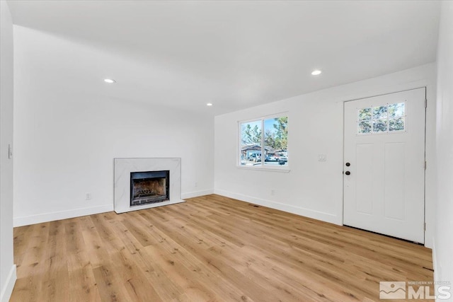 unfurnished living room featuring a premium fireplace and light hardwood / wood-style floors