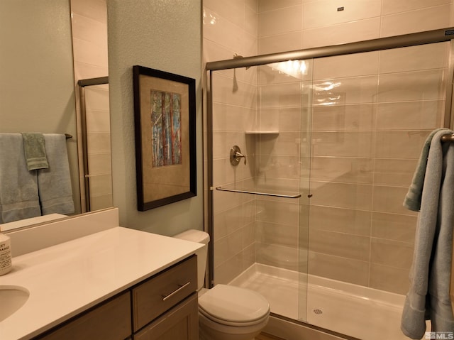 bathroom with vanity, toilet, and a shower with shower door