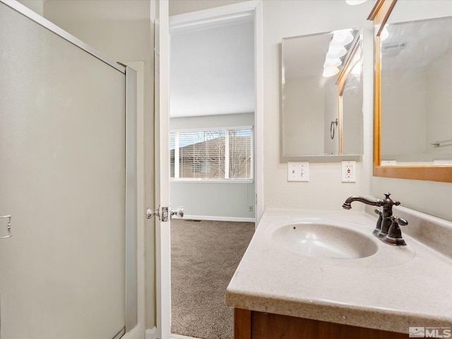 bathroom featuring a shower with door and vanity