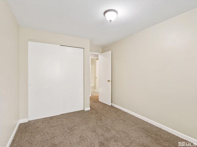 unfurnished bedroom featuring carpet flooring, a textured ceiling, and a closet