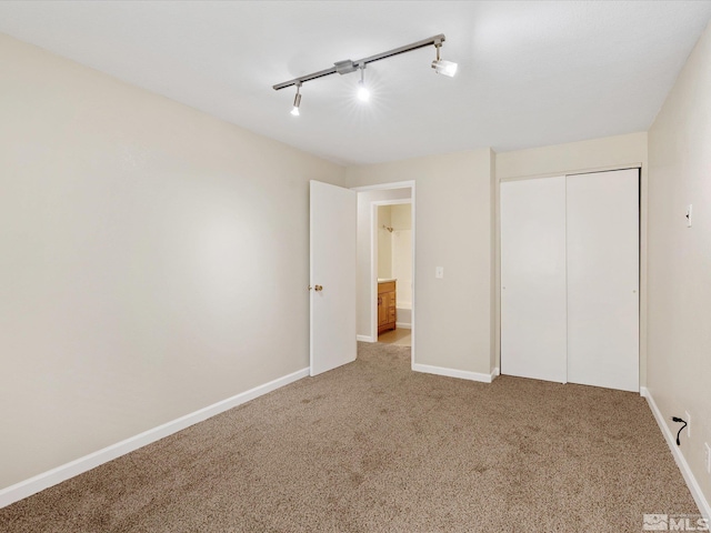 unfurnished bedroom with carpet, a closet, and track lighting