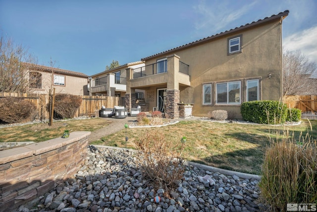 rear view of property featuring a yard, a balcony, and a patio area