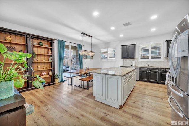 kitchen with stainless steel fridge, light hardwood / wood-style floors, gray cabinets, a kitchen island, and hanging light fixtures