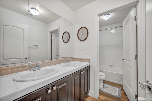 full bathroom with vanity, toilet, wood-type flooring, and bathing tub / shower combination