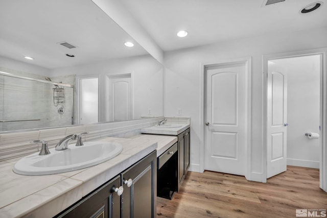 bathroom with wood-type flooring, vanity, and a shower with shower door