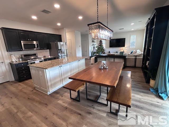 kitchen with a center island, white cabinets, light hardwood / wood-style flooring, light stone countertops, and appliances with stainless steel finishes