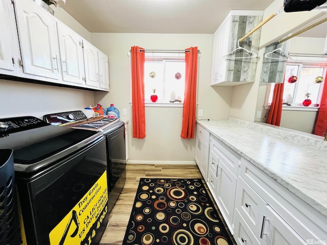 laundry room with washing machine and dryer, cabinets, and light hardwood / wood-style floors