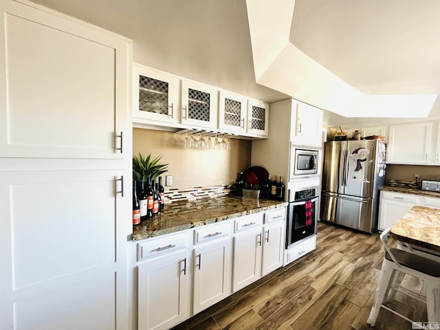 kitchen with dark stone counters, white cabinetry, dark hardwood / wood-style flooring, and stainless steel appliances