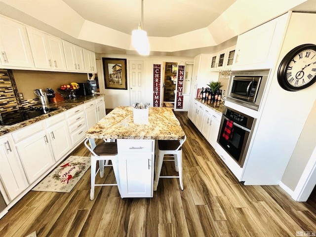 kitchen featuring white cabinets, a kitchen breakfast bar, a kitchen island, and appliances with stainless steel finishes