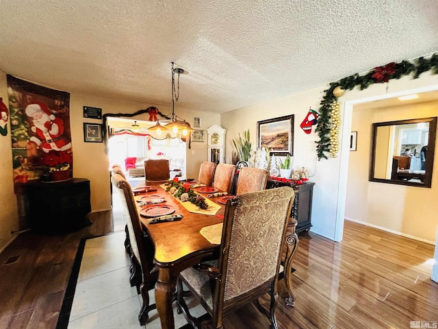 dining room featuring wood-type flooring and a textured ceiling