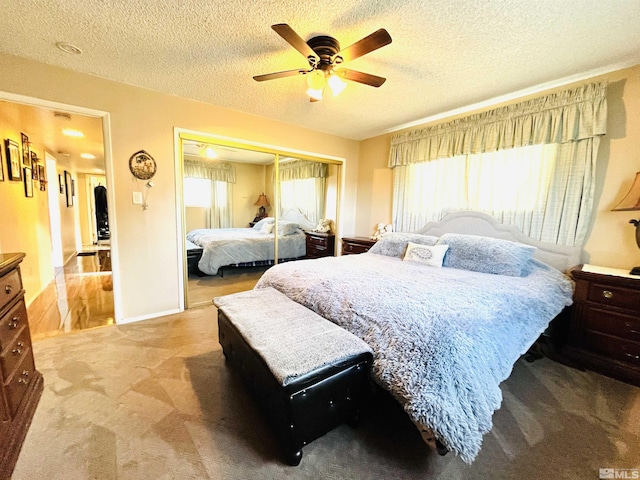 carpeted bedroom featuring multiple windows, a textured ceiling, a closet, and ceiling fan