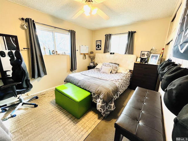 carpeted bedroom featuring ceiling fan and a textured ceiling