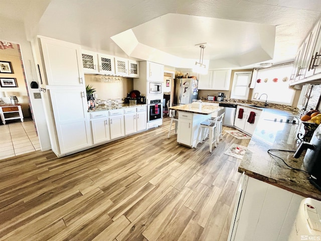 kitchen featuring a breakfast bar, appliances with stainless steel finishes, a center island, and a raised ceiling