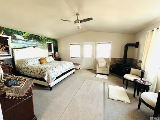 carpeted bedroom featuring ceiling fan, a wood stove, and vaulted ceiling