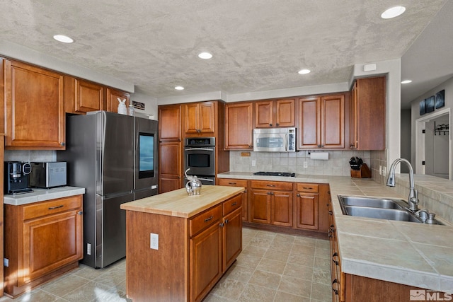 kitchen featuring sink, appliances with stainless steel finishes, tasteful backsplash, a kitchen island, and kitchen peninsula