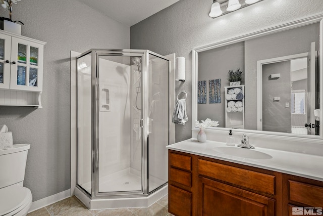 bathroom featuring toilet, vanity, tile patterned floors, and a shower with shower door