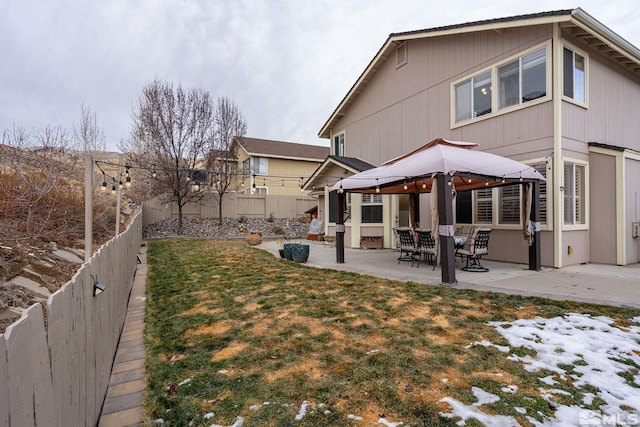 snow covered rear of property featuring a gazebo, a patio, and a lawn