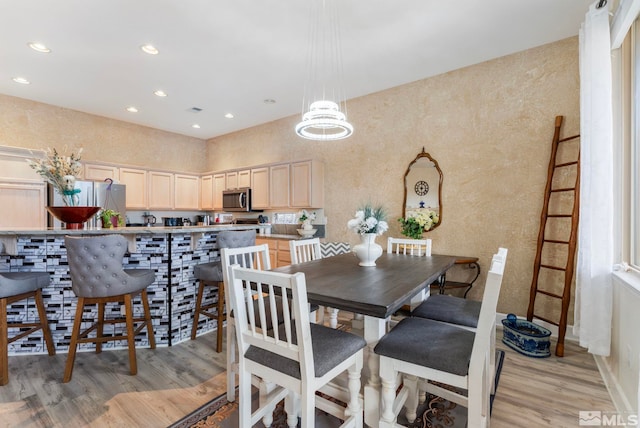 dining area with light hardwood / wood-style floors and a chandelier