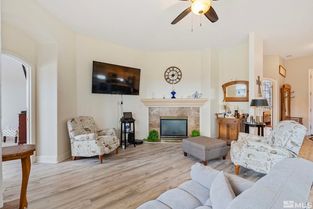 living room featuring a fireplace, ceiling fan, and light hardwood / wood-style flooring