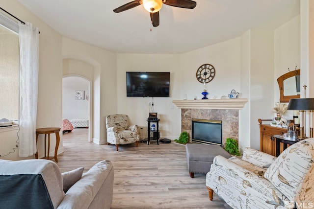 living room with a tile fireplace, a wealth of natural light, light hardwood / wood-style floors, and ceiling fan