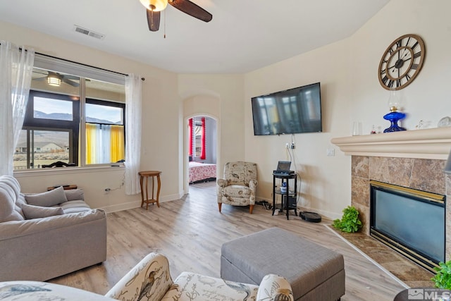 living room with ceiling fan, a fireplace, and light hardwood / wood-style flooring