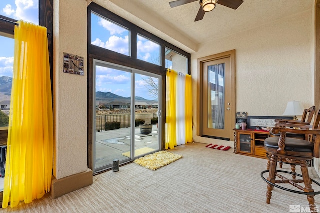 doorway featuring a mountain view, a textured ceiling, light colored carpet, and ceiling fan