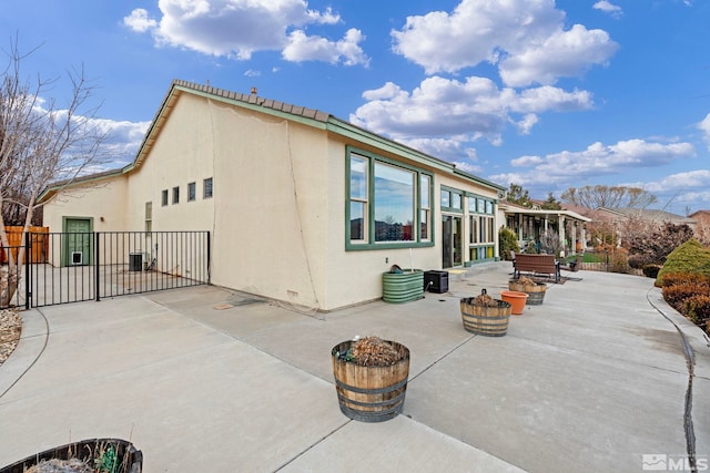 back of property with central air condition unit, a patio, and an outdoor fire pit