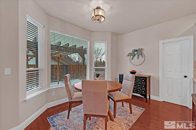 dining area featuring a healthy amount of sunlight, dark hardwood / wood-style flooring, and an inviting chandelier