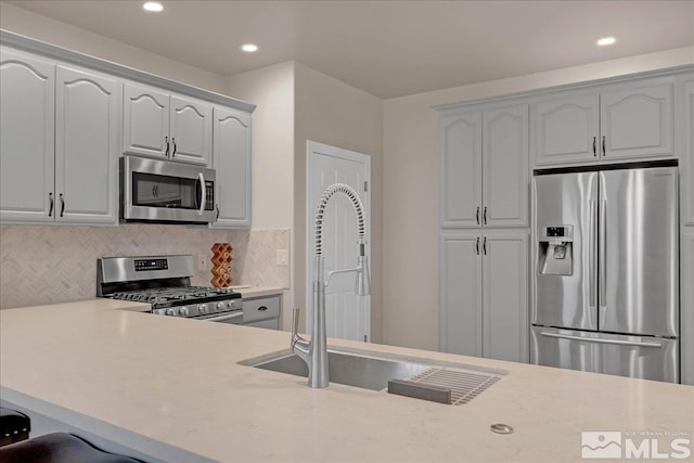 kitchen featuring backsplash, kitchen peninsula, sink, and stainless steel appliances