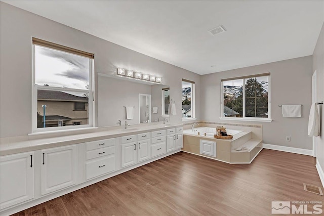 bathroom featuring hardwood / wood-style floors, vanity, and a tub to relax in