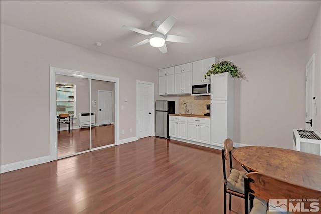 kitchen with backsplash, ceiling fan, sink, white cabinetry, and stainless steel refrigerator