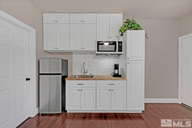 kitchen featuring white cabinets, sink, and stainless steel refrigerator