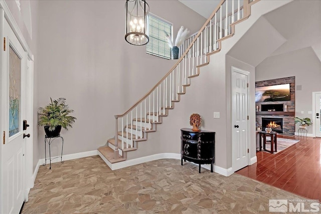 entrance foyer featuring a notable chandelier, a towering ceiling, and a fireplace